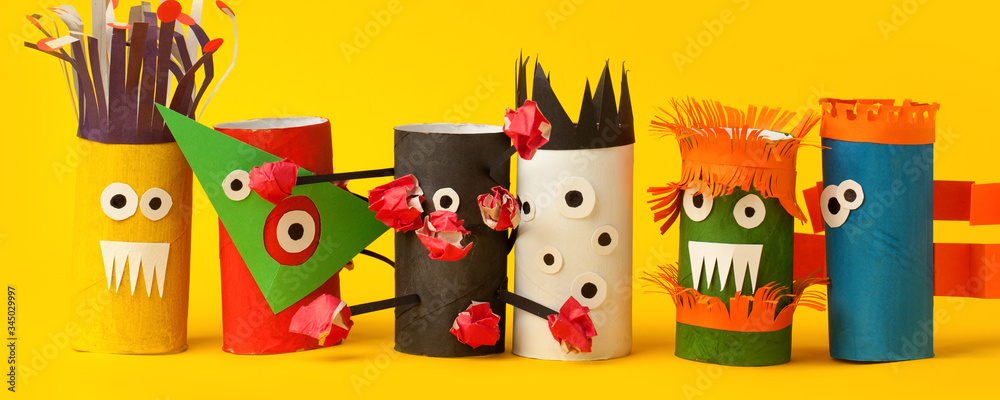 Fototapeta premium Kids art therapy, coronavirus pandemic. Halloween crafts, paper monsters on blue paper background with copy space for text. Concept handcraft, diy, creative idea from toilet tube, recycle