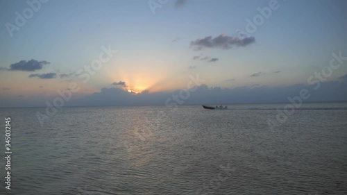 Lockdown shot of boat moving in sea against sky during sunset - Belize City, Belize photo