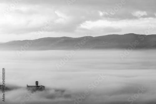 An epic view of St.Francis church in Assisi town (Umbria) above a sea of fog at dawn