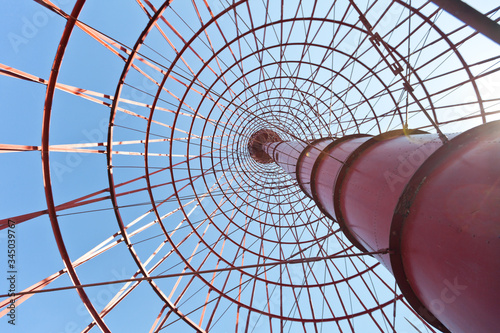 The metal construction of the lighthouse. The picture below. Hyperboloid technology. The metal is painted red. In the background is a blue sky. photo