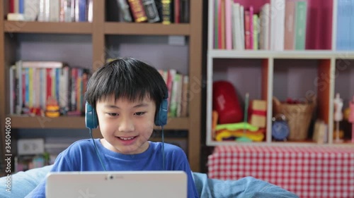 Happy young asian boy while connection on video call at home speaking looking and smiling at camera talking make video , education concept