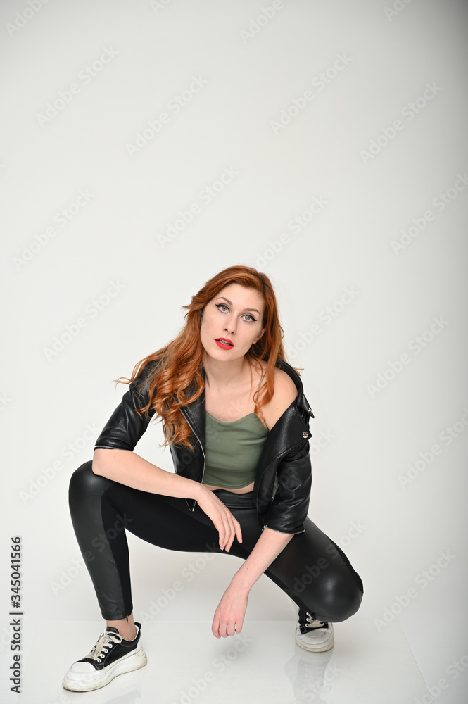 Portrait of a young pretty girl with beautiful hair in a green T-shirt and black clothes on a white background. Woman shows emotions changing poses sitting on the floor. Portrait of a young pretty girl with beautiful hair in a green T-shirt and black clothes on a white background. Woman shows emotions changing poses sitting on the floor.