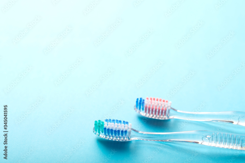 A pair of transparent plastic toothbrushes on blue background. A pair of transparent plastic toothbrushes on blue background.