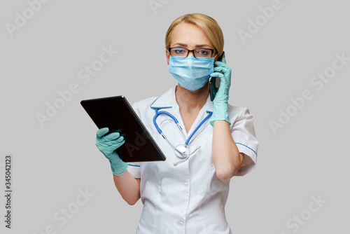medical doctor nurse woman wearing protective mask and gloves - holding tablet pc and mobile phone