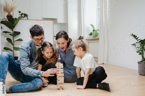 Family building tower from blocks, taking turns, picking and placing on top