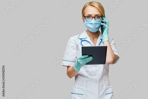 medical doctor nurse woman wearing protective mask and gloves - holding tablet pc and mobile phone