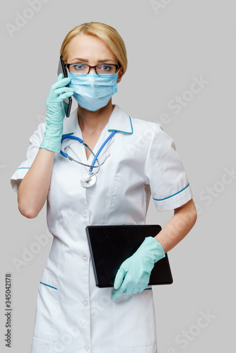 medical doctor nurse woman wearing protective mask and gloves - holding tablet pc and mobile phone