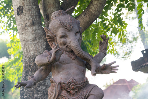 A ganesha statue against the background of the tree where the sunlight leaks
