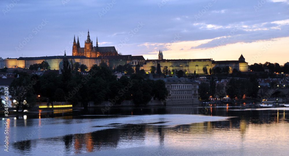 Panorama of the Vltava and the slightly illuminated St. Vitas Cathedral. View from the waterfront. Good summer evening in the Czech Republic.