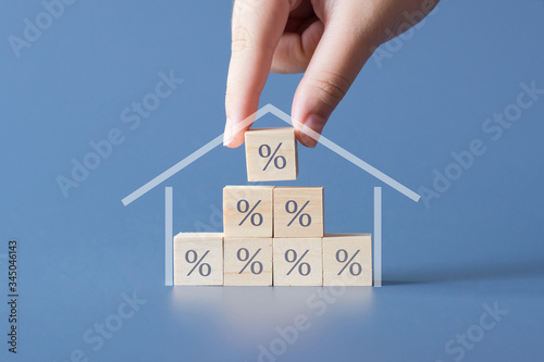 Hand building a house by wooden cubics with the percentage sign on them.Concept of Interest rate financial  mortgage rates,home loans,home refinance.