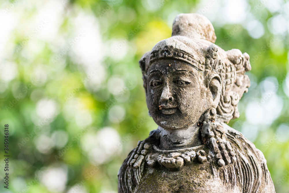 Traditional stone statue in Balinese landscape in soft focus