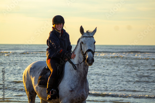 horse riding on the beach with a sunset, water, sand. Girls having fun