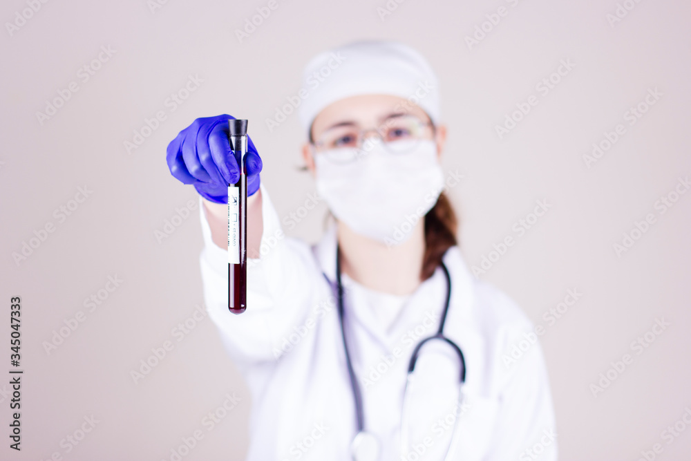 Nurse with respirator mask holding a tube with blood test result for coronavirus