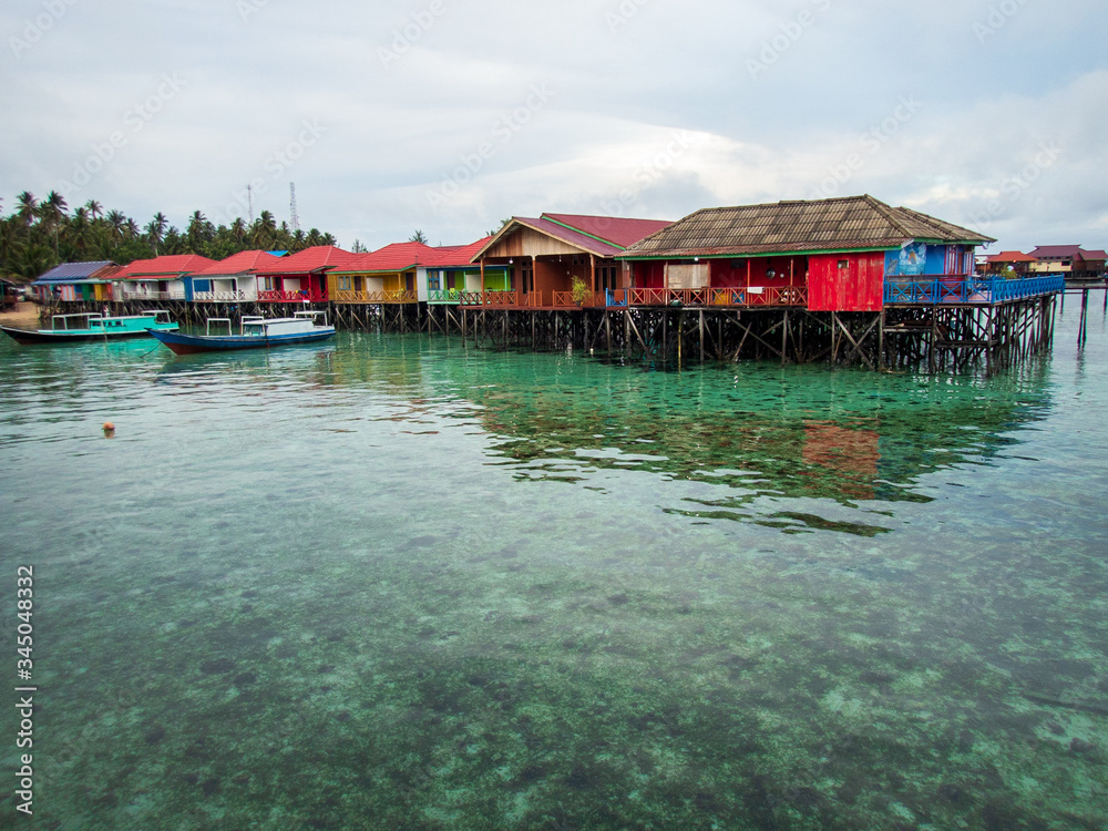 Colorful water cottages and boats at Derawan Island, North Kalimantan, Indonesia.  Leisure and travel.