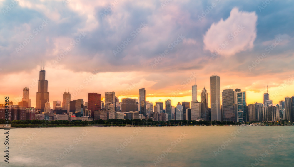  Chicago skyline at sunset with cloudy sky and reflection in water.