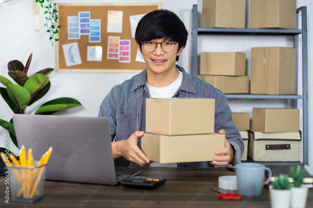 Asian business man startup SME entrepreneur or freelance working in a cardboard box prepares delivery box for customer, Online selling, e-commerce, packaging and shipping concept. Asian business man startup SME entrepreneur or freelance working in a cardboard box prepares delivery box for customer, Online selling, e-commerce, packaging and shipping concept.