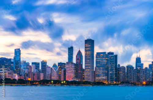  Chicago skyline at sunset with cloudy sky and reflection in water.