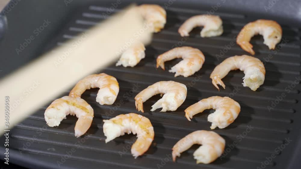 Woman fries prawns on the grill. Preparing a Warm Shrimp Salad Woman fries prawns on the grill. Preparing a Warm Shrimp Salad