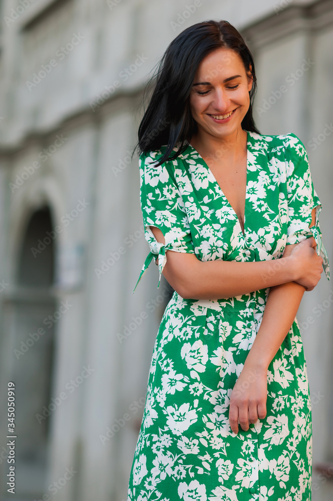 dark-haired girl walks around the city and posing in a turquoise dress