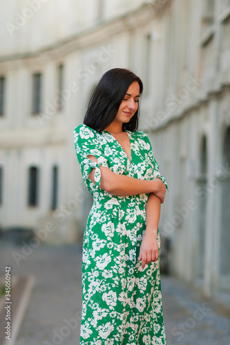 dark-haired girl walks around the city and posing in a turquoise dress