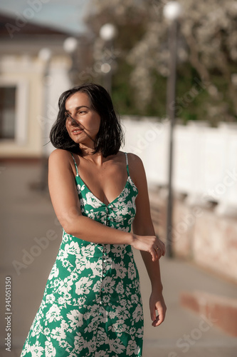 dark-haired girl walks around the city and posing in a turquoise dress