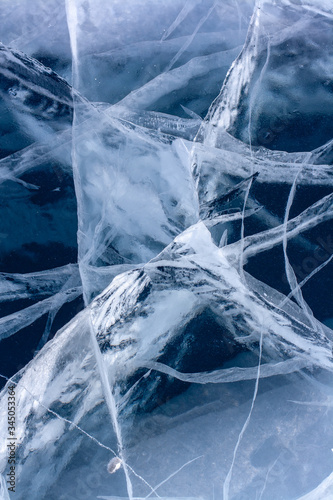 The natural texture of ice with deep cracks on Lake Baikal. Blue ice with white cracks. Vertical.