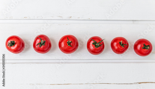 Row of cherry tomatoes on a white wooden table. Vegetarianism and a healthy lifestyle. Panorama format. Top view. Space for text.