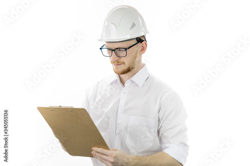 Handsome architector in hard hat makes notes on clipboard isolated on white background. Engineer reading instructions. Successful man from industrial sphere, heavy industry manufacturing concept