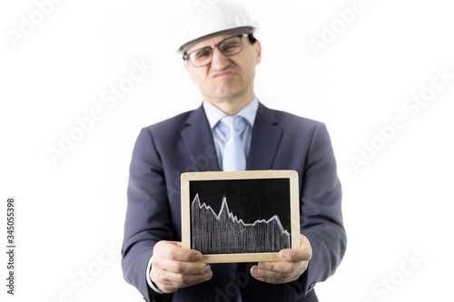 Displeased businessman holds sign with falling chart of oil quotes. Oil refinery industry, stock drop, quotes reduction, collapse of oil market, heavy petrochemical industry, futures exchange concept photo