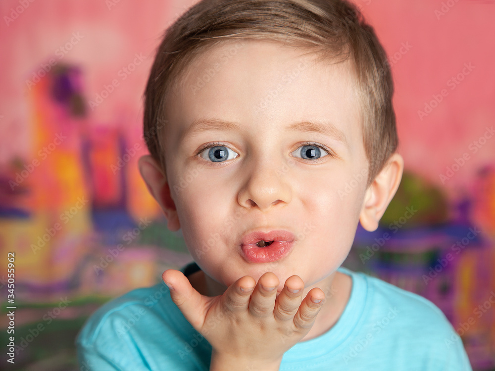 Portrait of a European blue-eyed boy blowing a kiss on a bright pink background. The child looks with a sly smile. Little ladies ' man. Portrait of a European blue-eyed boy blowing a kiss on a bright pink background. The child looks with a sly smile. Little ladies ' man.