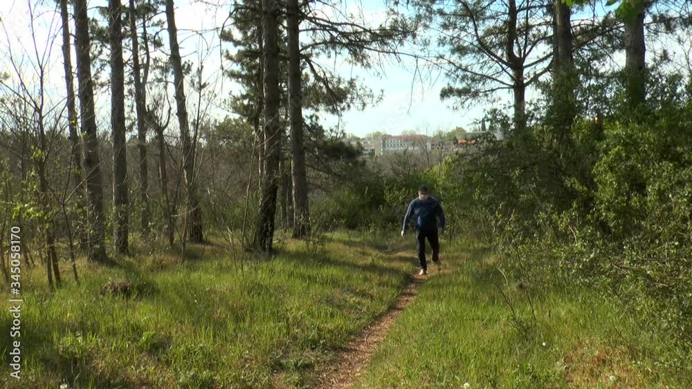 a man on a path in the forest takes off his face mask and breathes lightly with full breasts. Concept, people are looking for places protected from quarantine caused by the coronavirus pandemic. a man on a path in the forest takes off his face mask and breathes lightly with full breasts. Concept, people are looking for places protected from quarantine caused by the coronavirus pandemic.