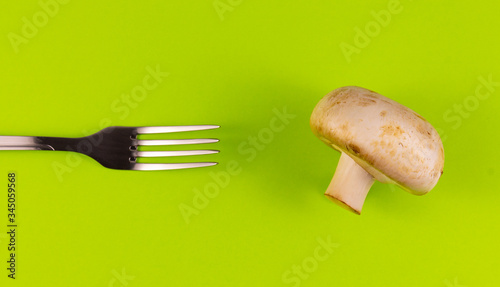 The fork is directed towards the champignon on a green background. Top view .copyspace for text. photo