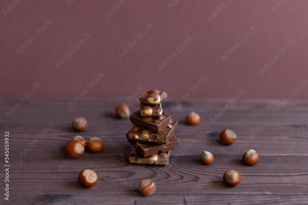 Pieces of dark chocolate with nazel nuts on brown wooden backgrouns