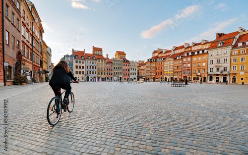 Woman on a bike rides on an empty Old Town Square in Warsaw, Poland