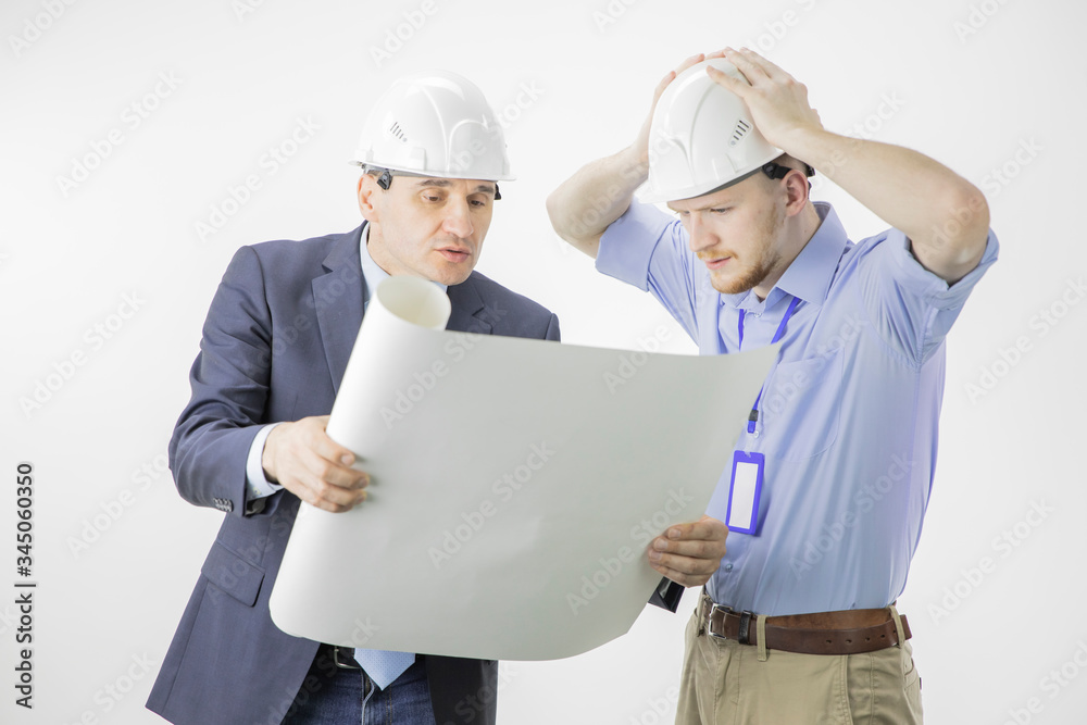 Head of project and chief engineer discussing mistakes and problems in architectural project blueprint. Engineer in hard hat grabbed head in panic. Construction, engineering and architecture concept Head of project and chief engineer discussing mistakes and problems in architectural project blueprint. Engineer in hard hat grabbed head in panic. Construction, engineering and architecture concept