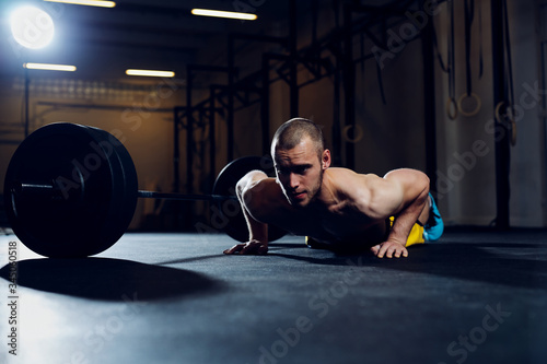 Athletic man exercise at gym doing burpee over the bar