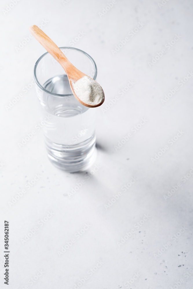 Collagen powder in spoon on glass of water, supplement, healthy and anti age concept flat lay on white background Collagen powder in spoon on glass of water, supplement, healthy and anti age concept flat lay on white background