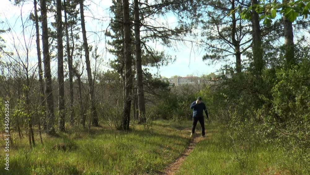 a man talking on a cell phone in a protective mask and gloves climbs a forest path. Concept, a person nowhere feels safe from the coronavirus pandemic a man talking on a cell phone in a protective mask and gloves climbs a forest path. Concept, a person nowhere feels safe from the coronavirus pandemic