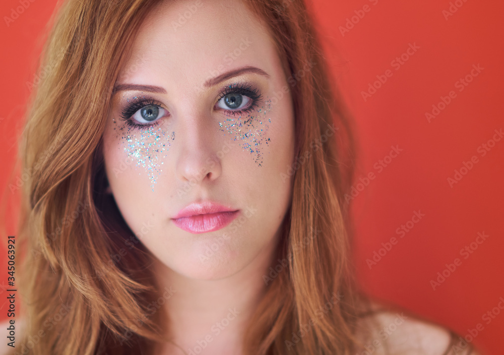 Beautiful gray eyed young caucasian woman with metallic colorful glitter make up and ginger red hair. Beautiful gray eyed young caucasian woman with metallic colorful glitter make up and ginger red hair.