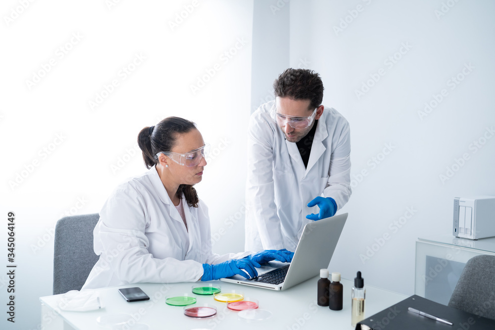 Young researchers or Scientists examining solution in petri dish at a laboratory. The researcher is analyzing the medicine related innovation. Biochemistry and Biotechnology concept