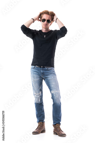 Cool macho redhead male fashion model adjusting hairstyle with both hands in hair. Full body isolated on white background. 