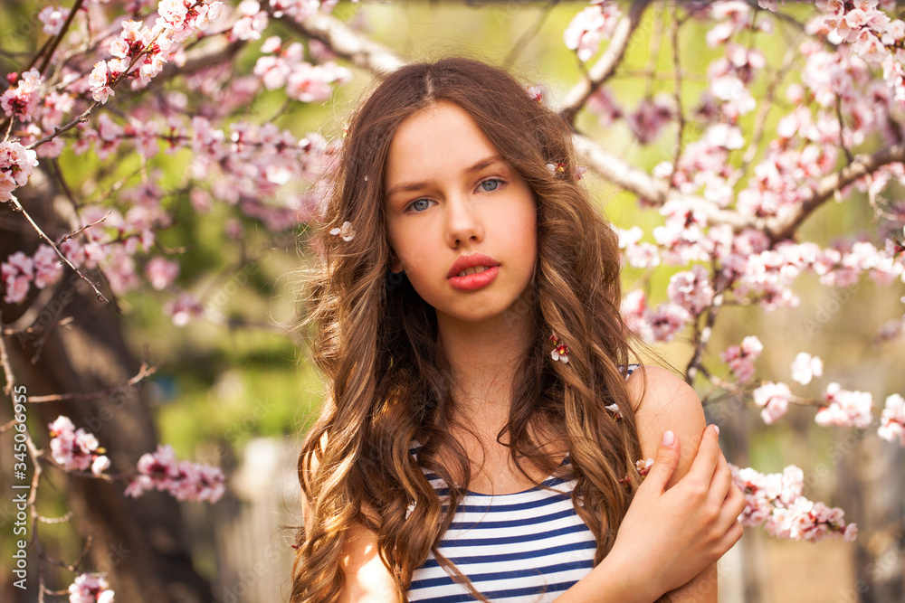 Young girl posing near blossom cherry tree with pink flowers Young girl posing near blossom cherry tree with pink flowers