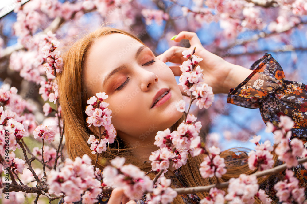 Young girl posing near blossom cherry tree with pink flowers Young girl posing near blossom cherry tree with pink flowers