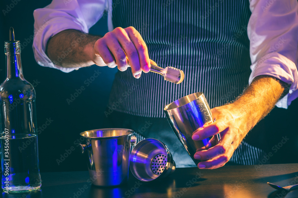 Obraz premium Bartender adding ice into cocktail shaker