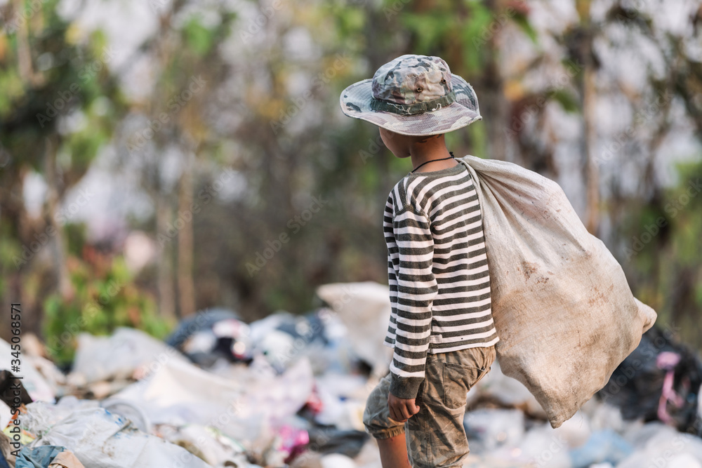 Obraz premium A poor boy collecting garbage waste from a landfill site. Concept of livelihood of poor children.Child labor. Child labor, human trafficking, Poverty concept