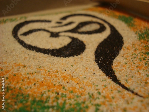 Om. Vedic culture. The symbol of the universe. Om sound in yoga is used as a mantra. Sand painting. Close-up. Used black, white, yellow and green colors.Spiritual sign in Hinduism and Buddhism.Harmony