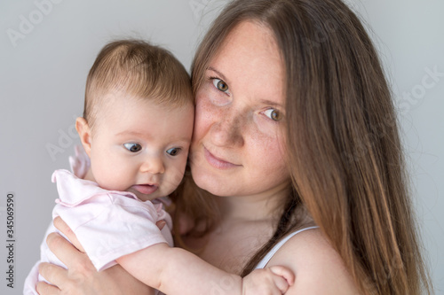 Mother cuddling toddler daughter on shoulder