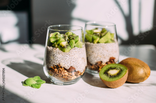 Healthy breakfast. chia pudding with kiwi and granola in glass on white background