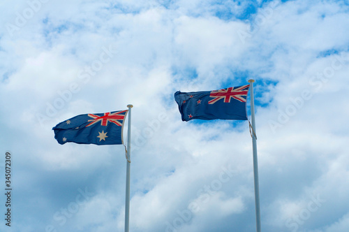 New Zealand and Australian flags against cloudy sky
