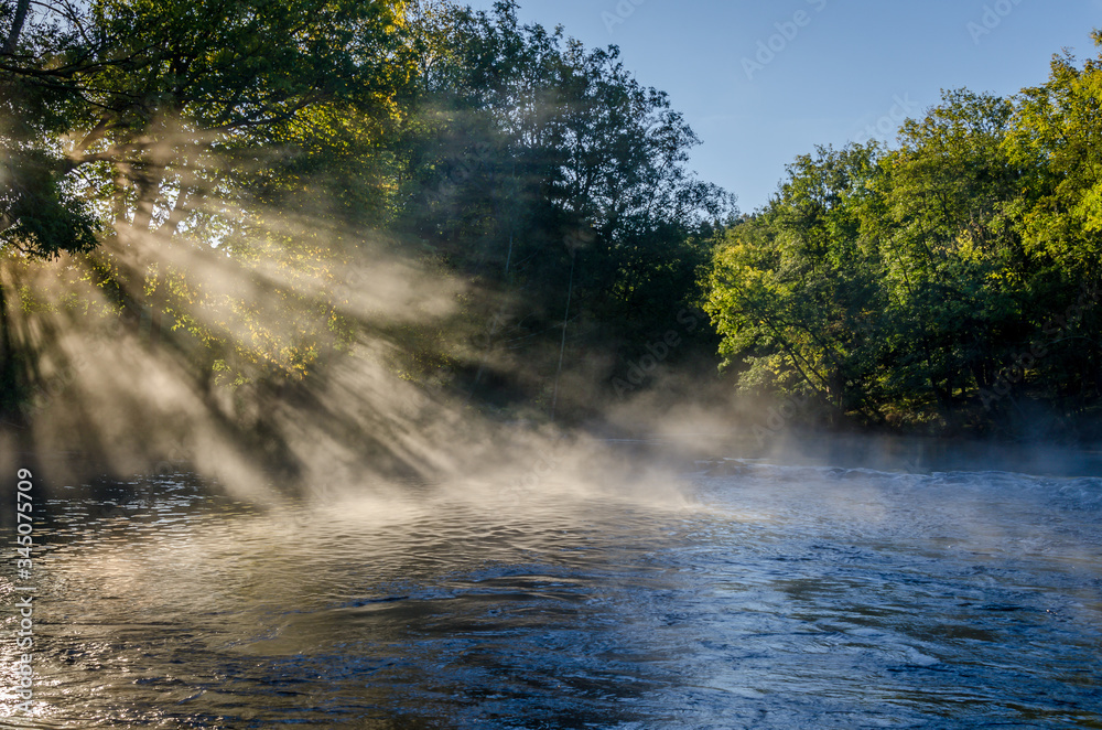 Magical morning, fog and sunshine at a river just outside Gothenburg, Sweden. View of a beautiful landscape, with trees, water, morning light and mist. Natural background with copy space.